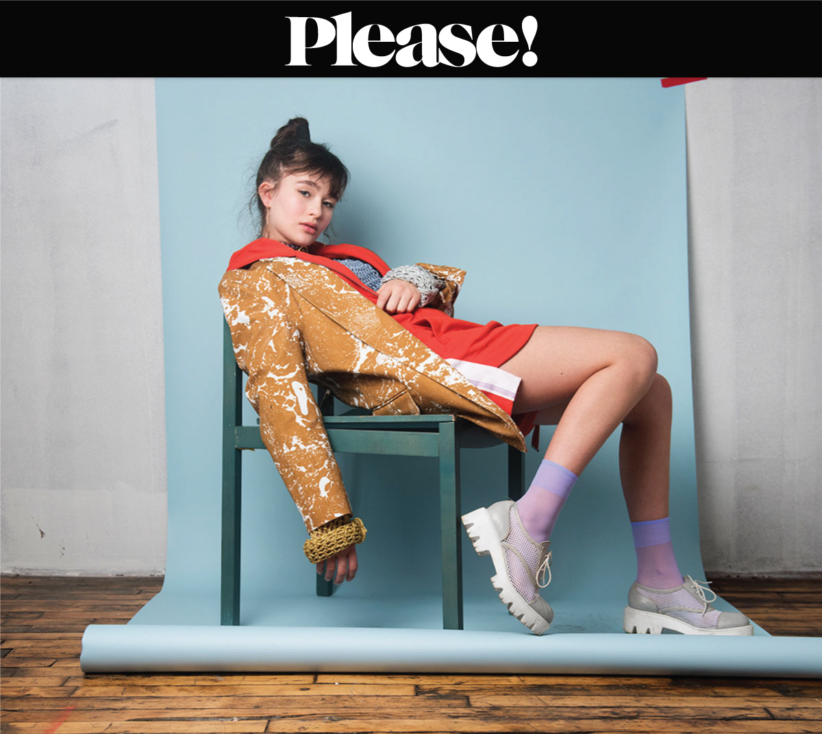 Girl stting on a chair with a blue backdrop wearing colored clothes